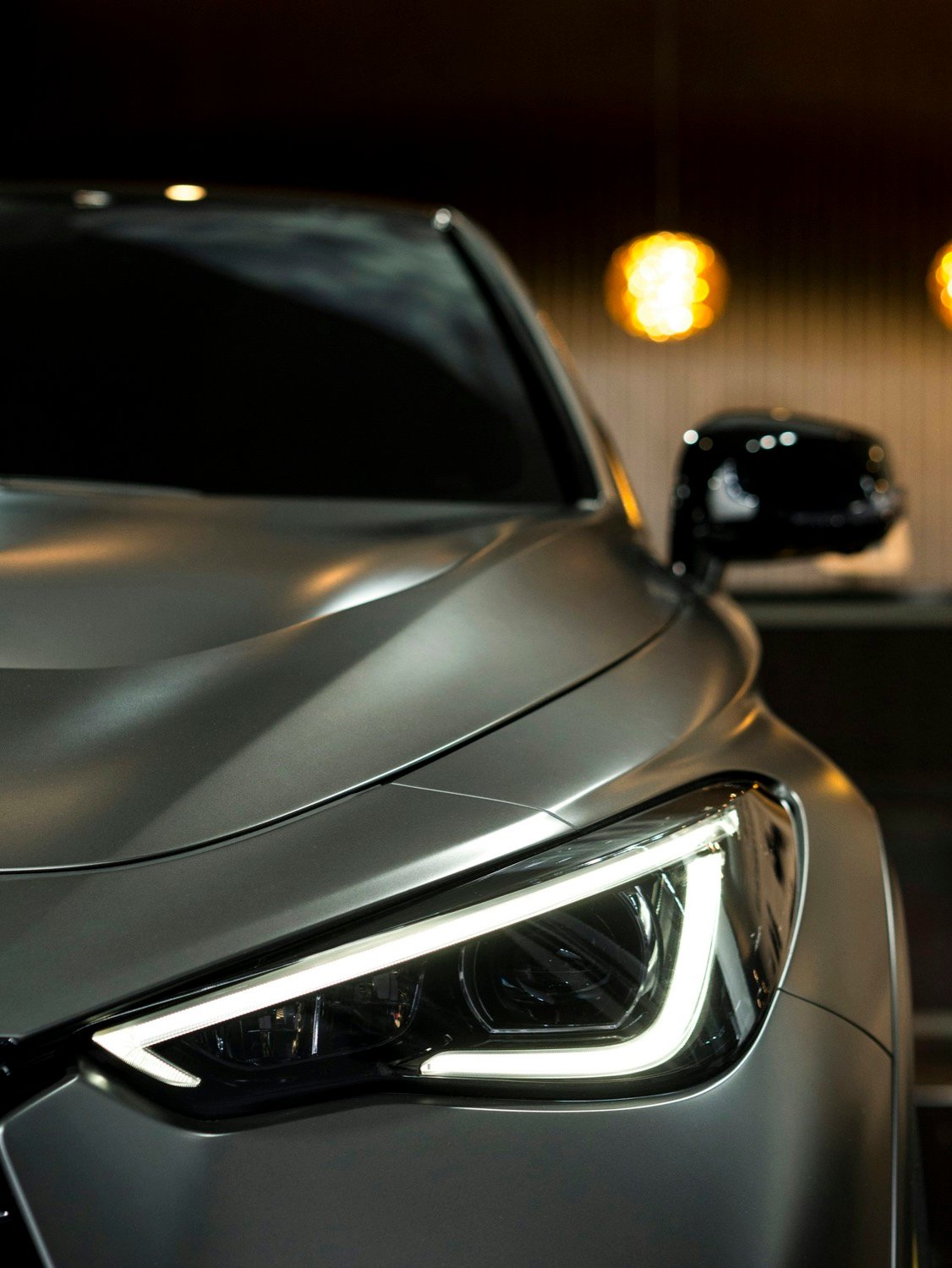Close-up of the LED headlight and front wing of a dark luxury saloon.